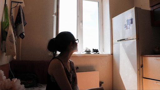 A girl stares out a kitchen window.