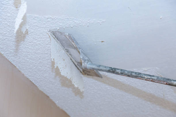 A scraper blade removing the texture on a popcorn ceiling.